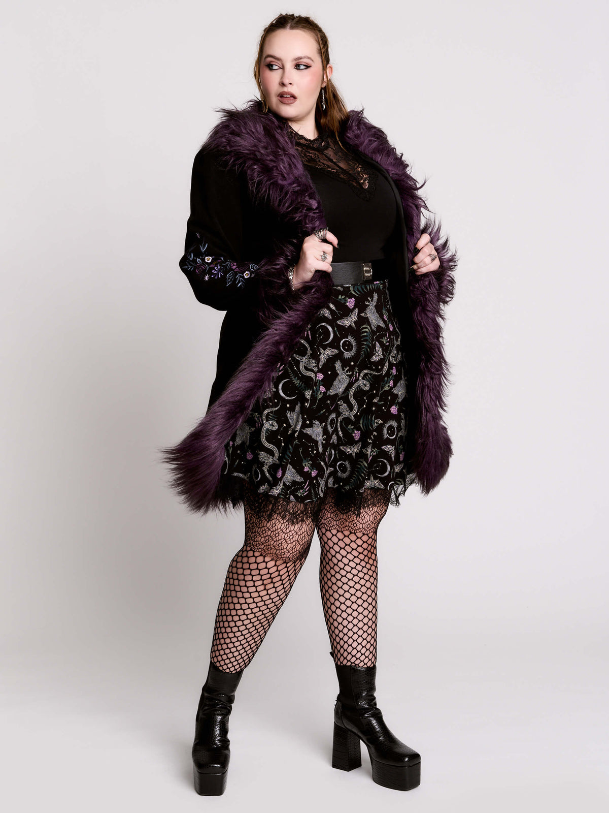 This mid-length black coat pairs a soft, suede-like finish with plush amethyst-purple faux fur trim