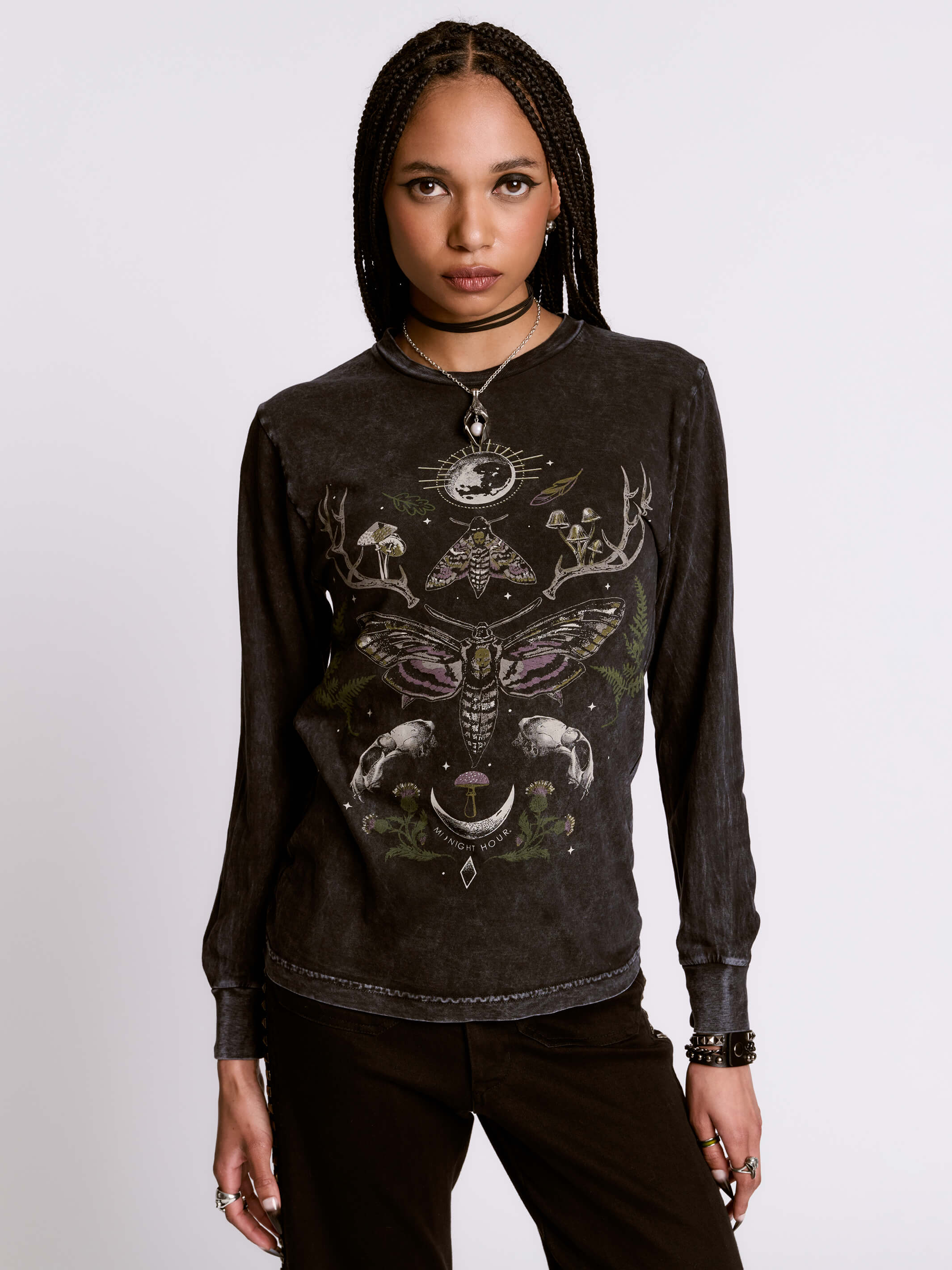 Person wearing a black long-sleeve shirt with intricate designs on a plain background
