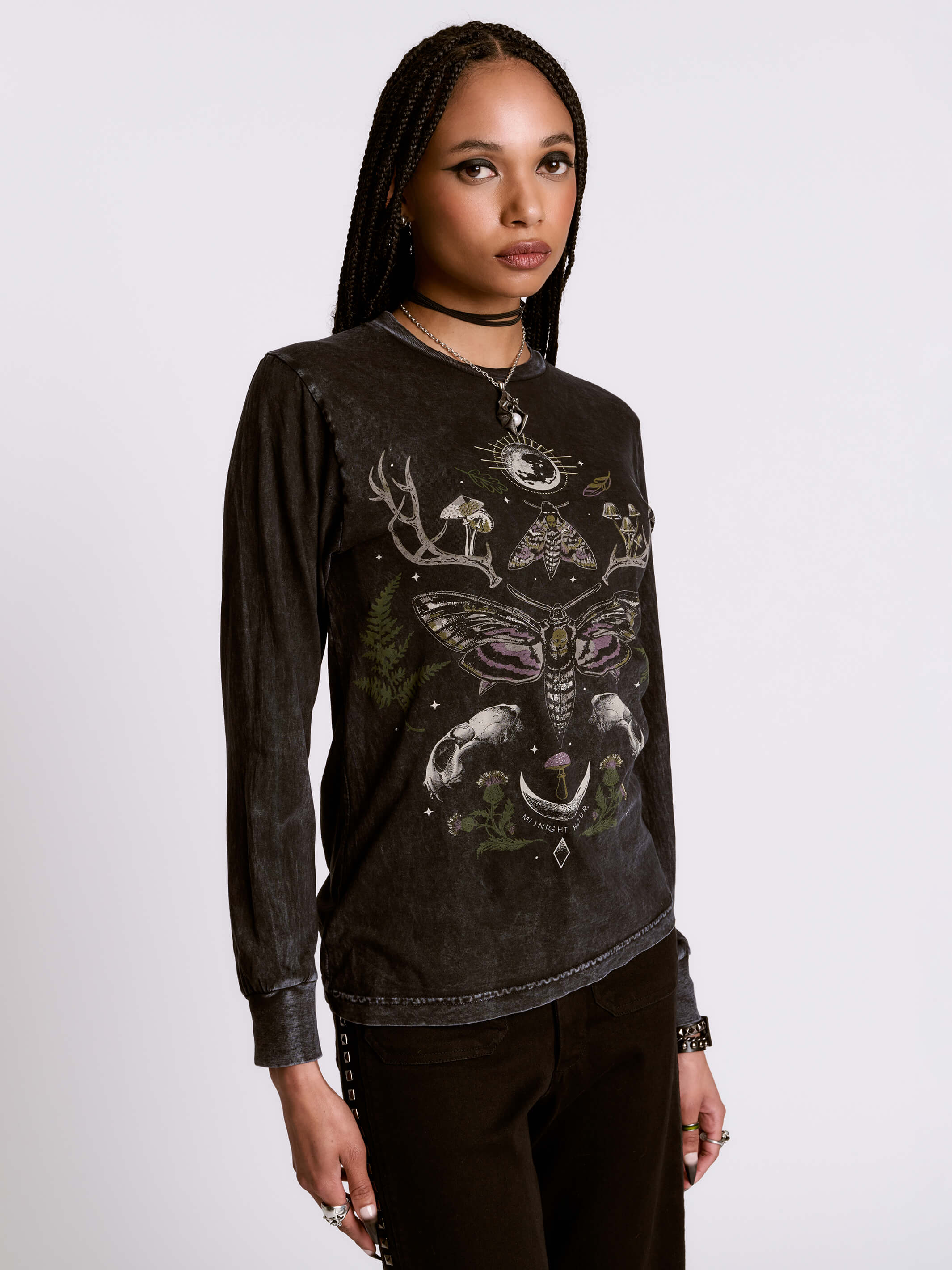 Woman wearing a black long-sleeve shirt with intricate designs on a white background