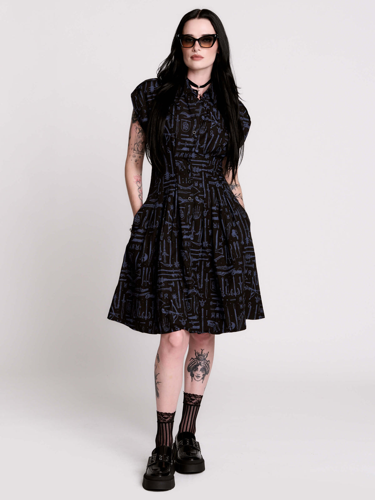 a button-front shirt dress featuring a striking medieval-inspired print with weaponry and macabre motifs.