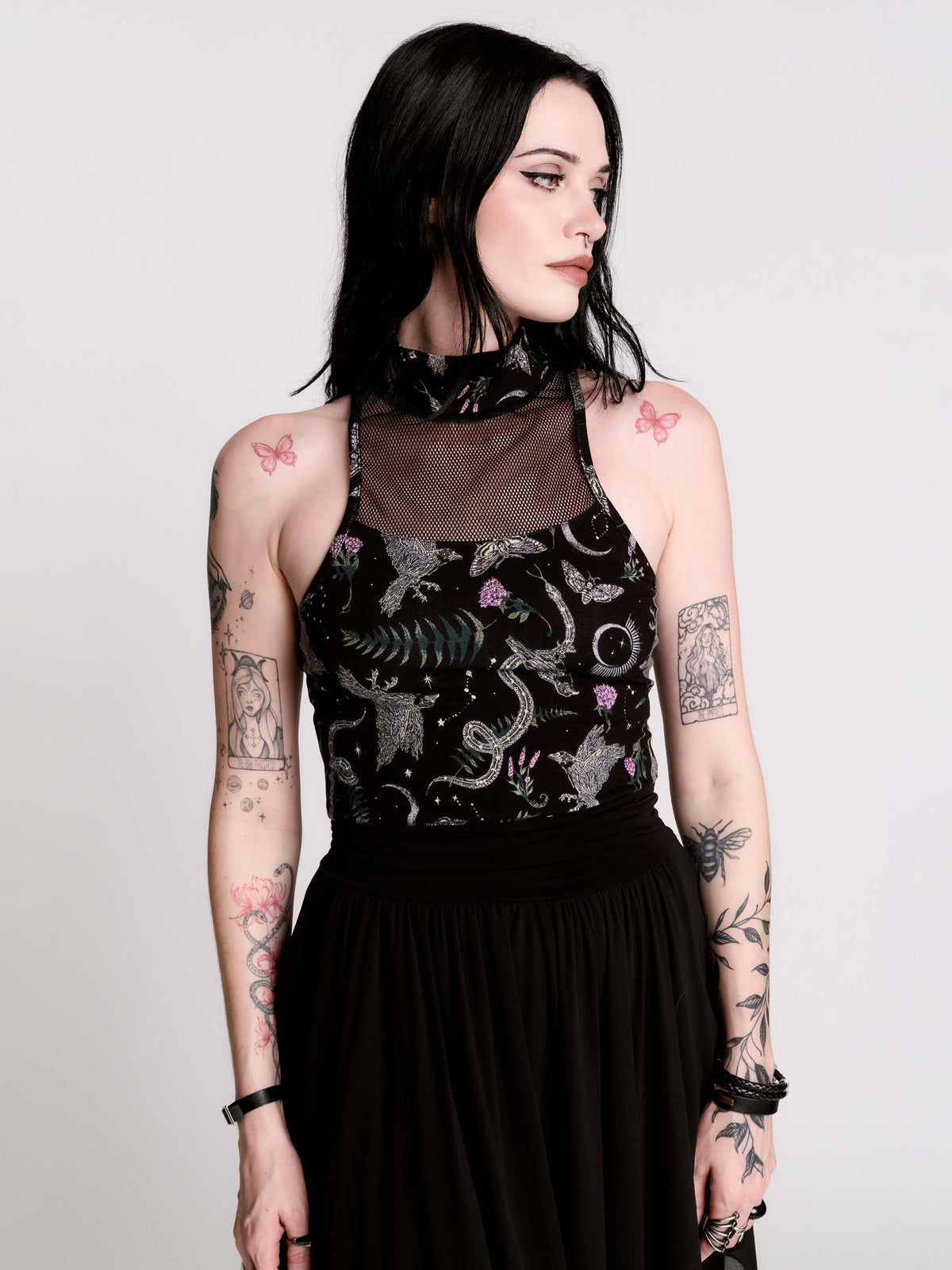 A black sleeveless top with a high mesh neck and an allover gothic-style print featuring silver snakes, moths, ravens and small pink floral accents.