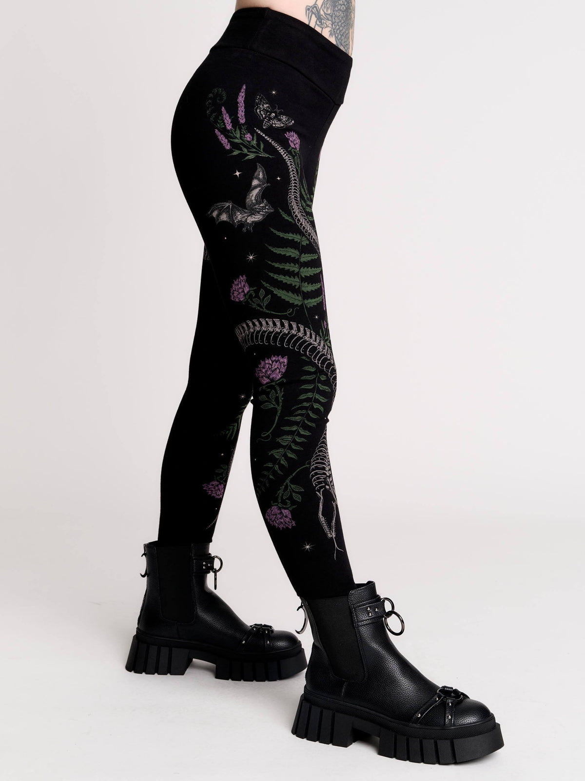 Black leggings with a detailed graphic print of a green fern, a purple flower, and a silver snake