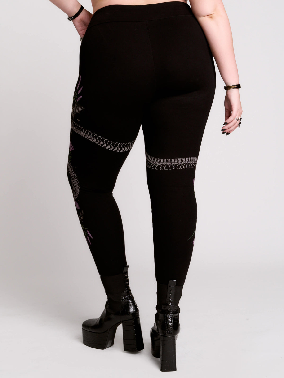 Black leggings with a detailed graphic print of a green fern, a purple flower, and a silver snake