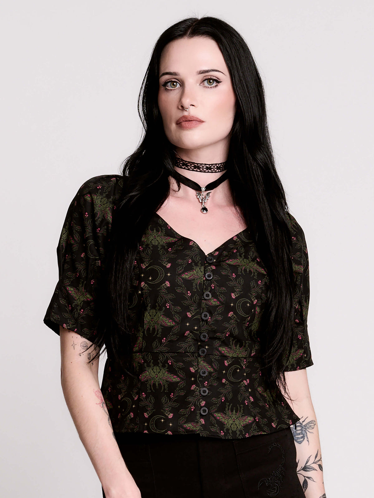 A short-sleeve button-up blouse featuring a dark green and black gothic pattern with pink accents.