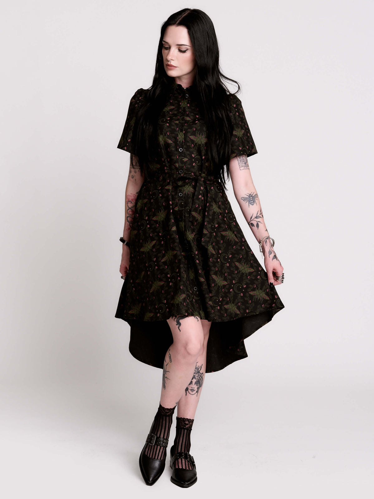 a short-sleeved high-low dress in black with a small red and green floral pattern.