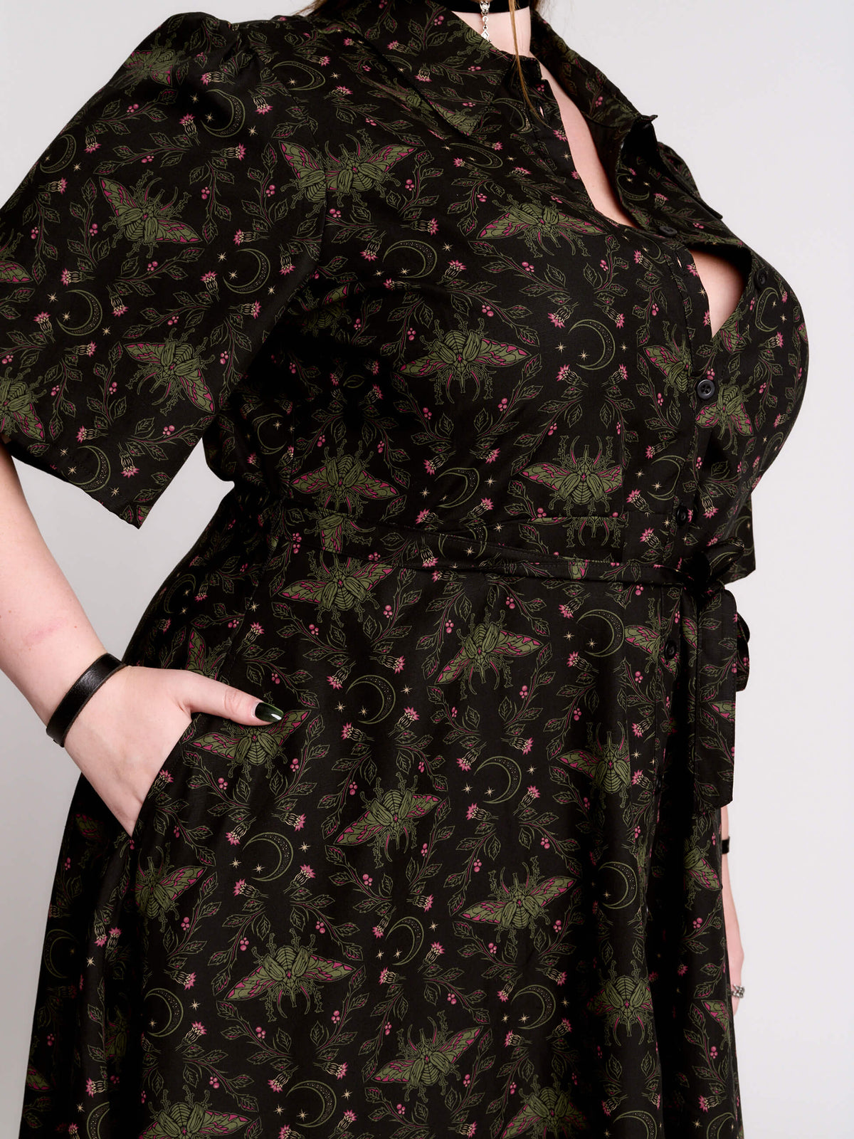 a short-sleeved high-low dress in black with a small red and green floral pattern.