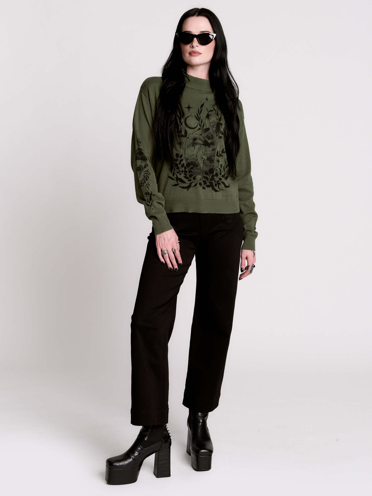 an olive green mock-neck sweater featuring a black gothic graphic