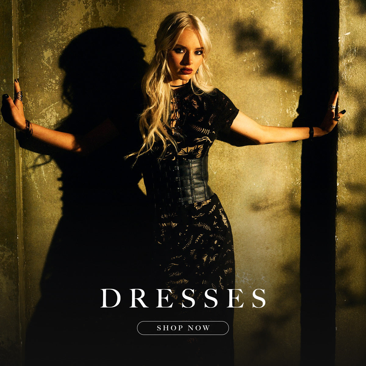 Woman in a black dress with arms outstretched against a textured wall, 'Dresses' text overlay.