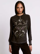 Person wearing a black long-sleeve shirt with intricate designs on a plain background