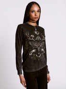 Woman wearing a black long-sleeve shirt with intricate designs on a white background