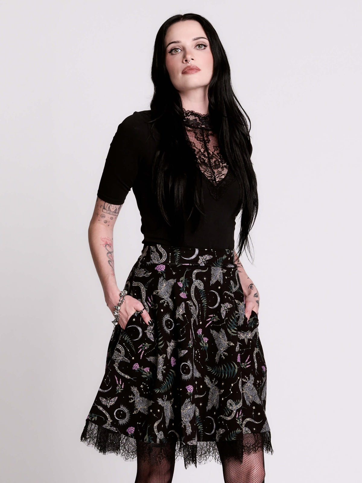 A  black flared skirt featuring a gray and purple gothic print with lace hem.