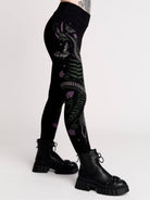 Black leggings with a detailed graphic print of a green fern, a purple flower, and a silver snake