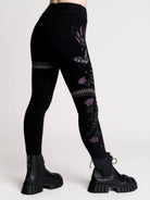 Black leggings with a detailed graphic print of a green fern, a purple flower, and a silver snake
