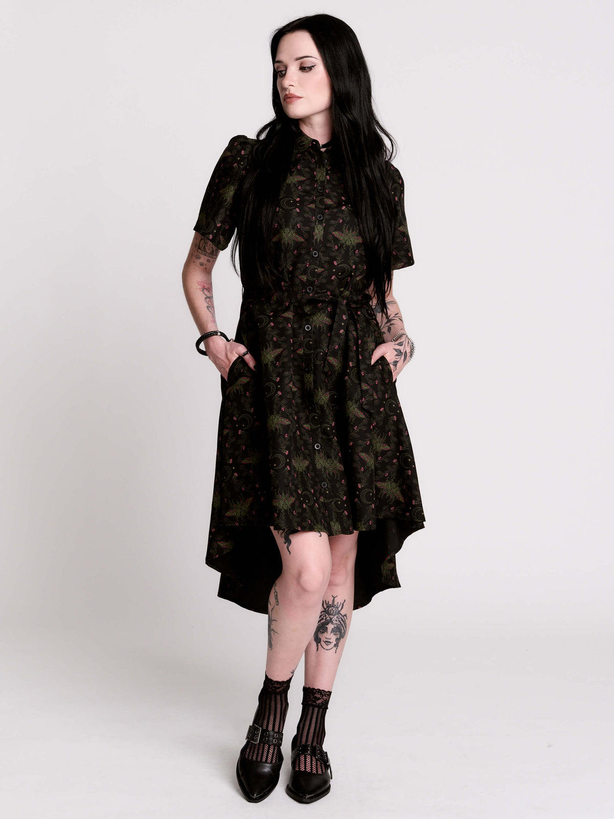 a short-sleeved high-low dress in black with a small red and green floral pattern.