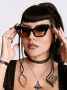 Woman wearing black cat-eye sunglasses with a neutral background
